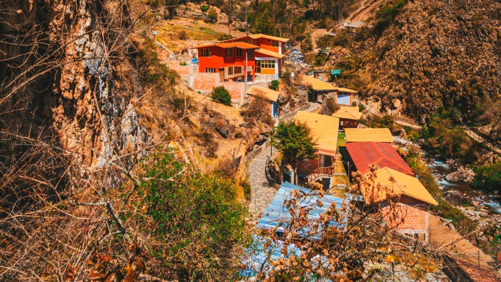 A picturesque view of Lares town in Peru, featuring traditional Andean houses, a winding road, and a river flowing through the valley.