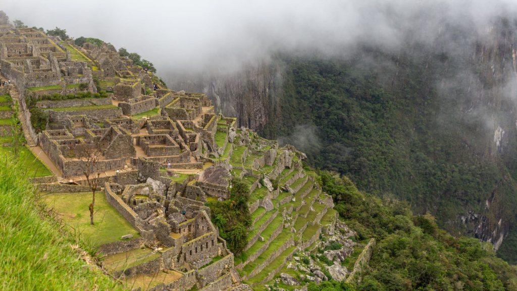 A breathtaking view of Machu Picchu, the ancient Inca citadel nestled in the Andes Mountains, surrounded by mist and lush greenery.
