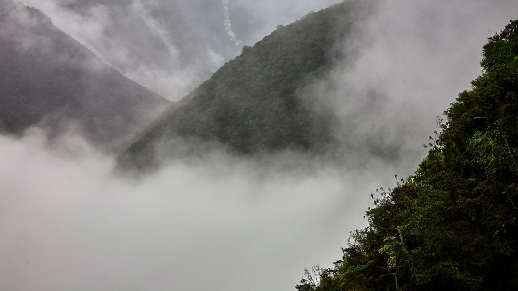 Fog covering the lush green mountains of the Andes, creating a mystical and dramatic landscape near Machu Picchu.