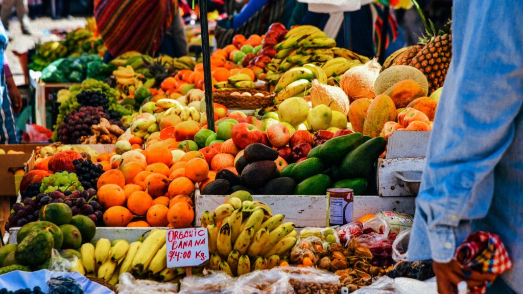 Fresh fruit stand in a local market in Cusco, featuring a variety of Andean products such as bananas, papayas, avocados, and pineapples - Xplor Machu Picchu