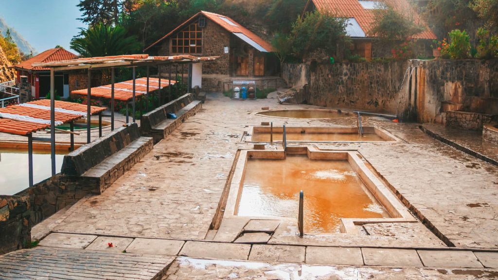 Peaceful view of Lares Hot Springs in Peru, featuring mineral-rich thermal pools, rustic stone pathways, and surrounding Andean architecture.