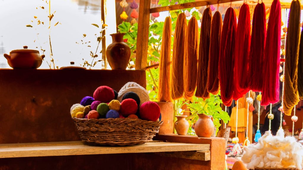 Artesanía textil andina con lanas teñidas naturalmente y ovillos de colores en un taller tradicional - Xplor Machu Picchu.