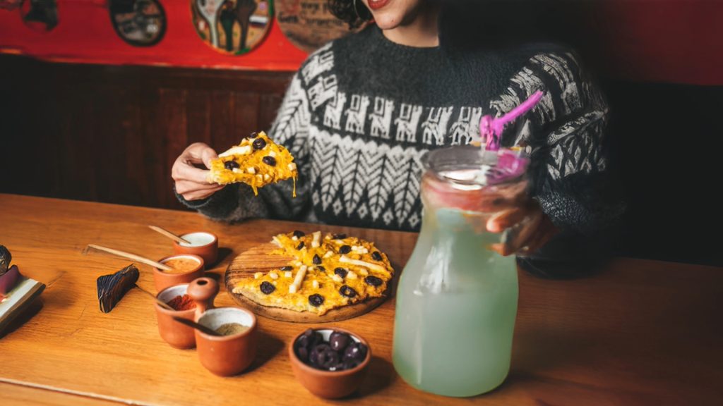 Woman enjoying Andean food in a cozy setting, capturing the flavorful side of Cusco’s nightlife - Xplor Machupicchu